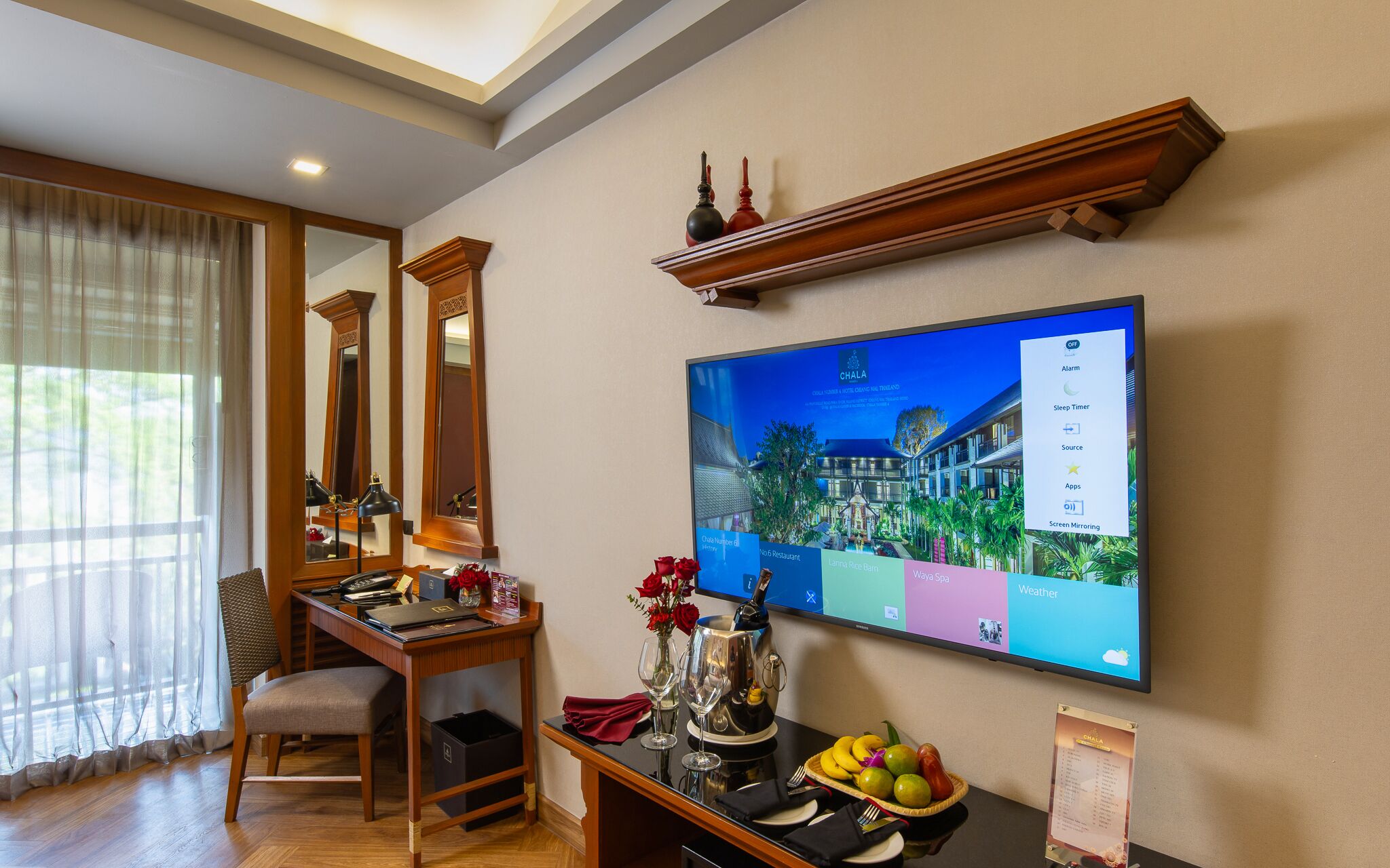 Une chambre d’hôtel équipée d’un bureau, d’une chaise et d’un téléviseur à écran plat affichant un menu numérique.