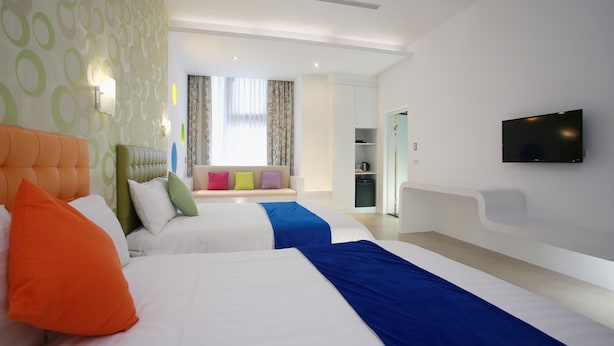 A hotel room with two beds, a TV, and a seating area with colorful cushions. - Green Life Spa (Jiaoxi)