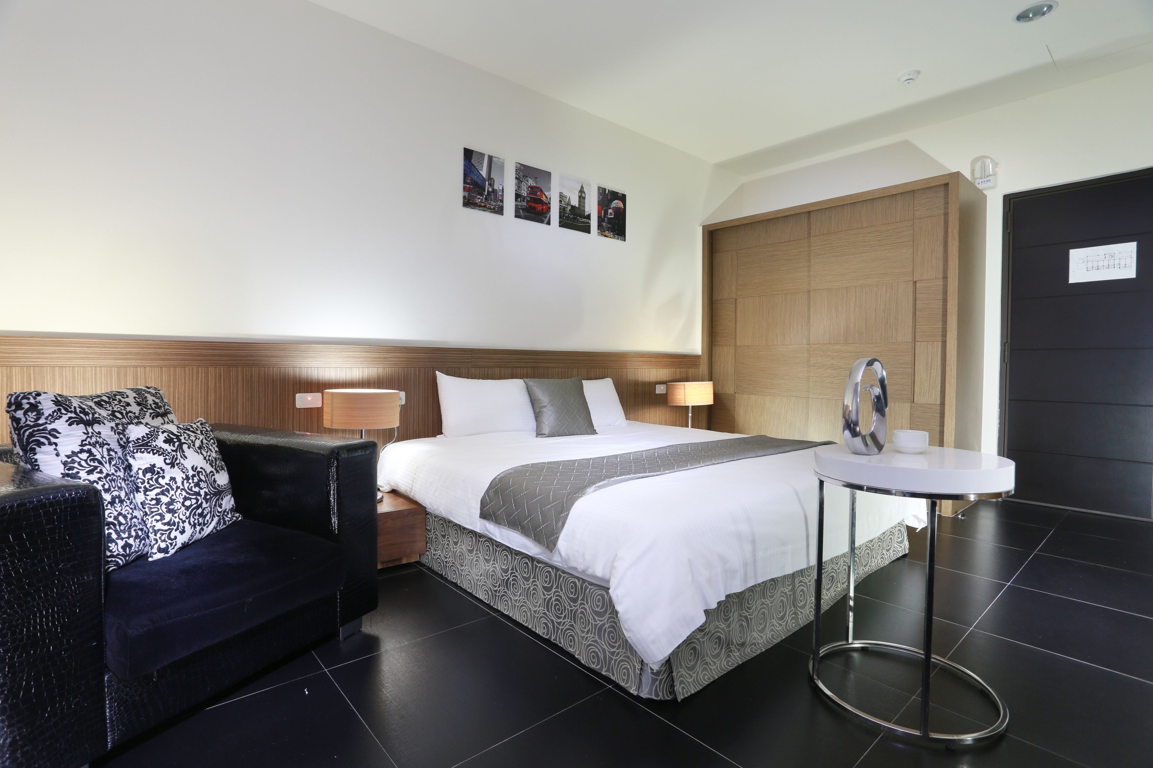 A hotel room with a bed, a sofa, a small table, and a wooden door.