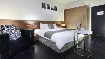 A hotel room with a bed, a sofa, a small table, and a wooden door.