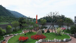 A landscaped garden with a stone pathway, red flowers, and a variety of plants. - Green Life Spa (Jiaoxi)