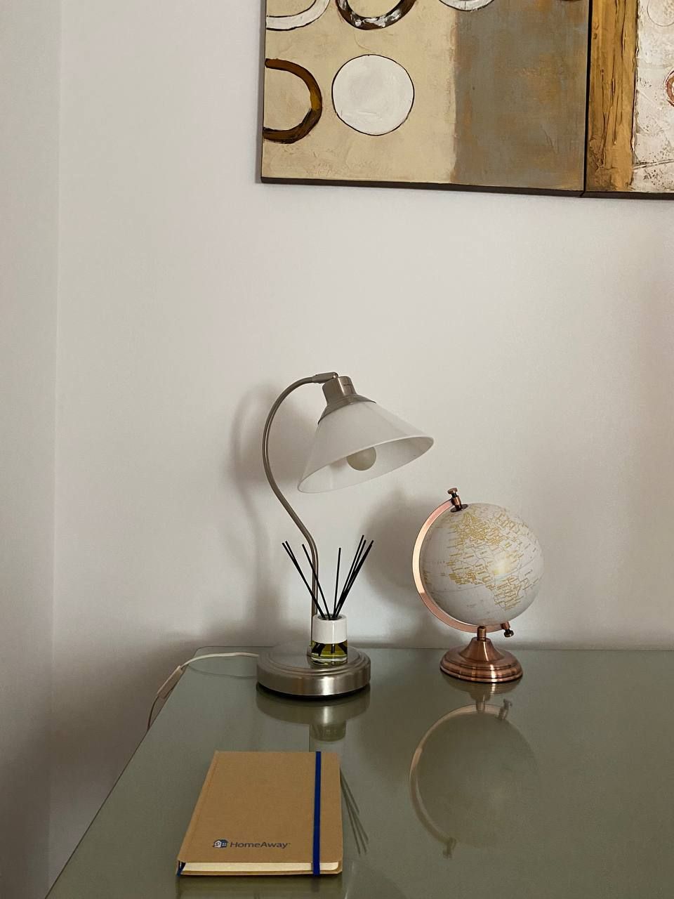 Un bureau avec une lampe, un globe terrestre et un carnet.