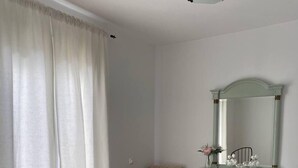Un dormitorio con cama, cómoda, silla y espejo.