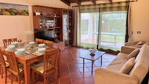 A dining area with a wooden table set for four, a television, and a cabinet with glass doors.