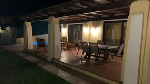 An outdoor patio area with a pool, dining table, and chairs.
