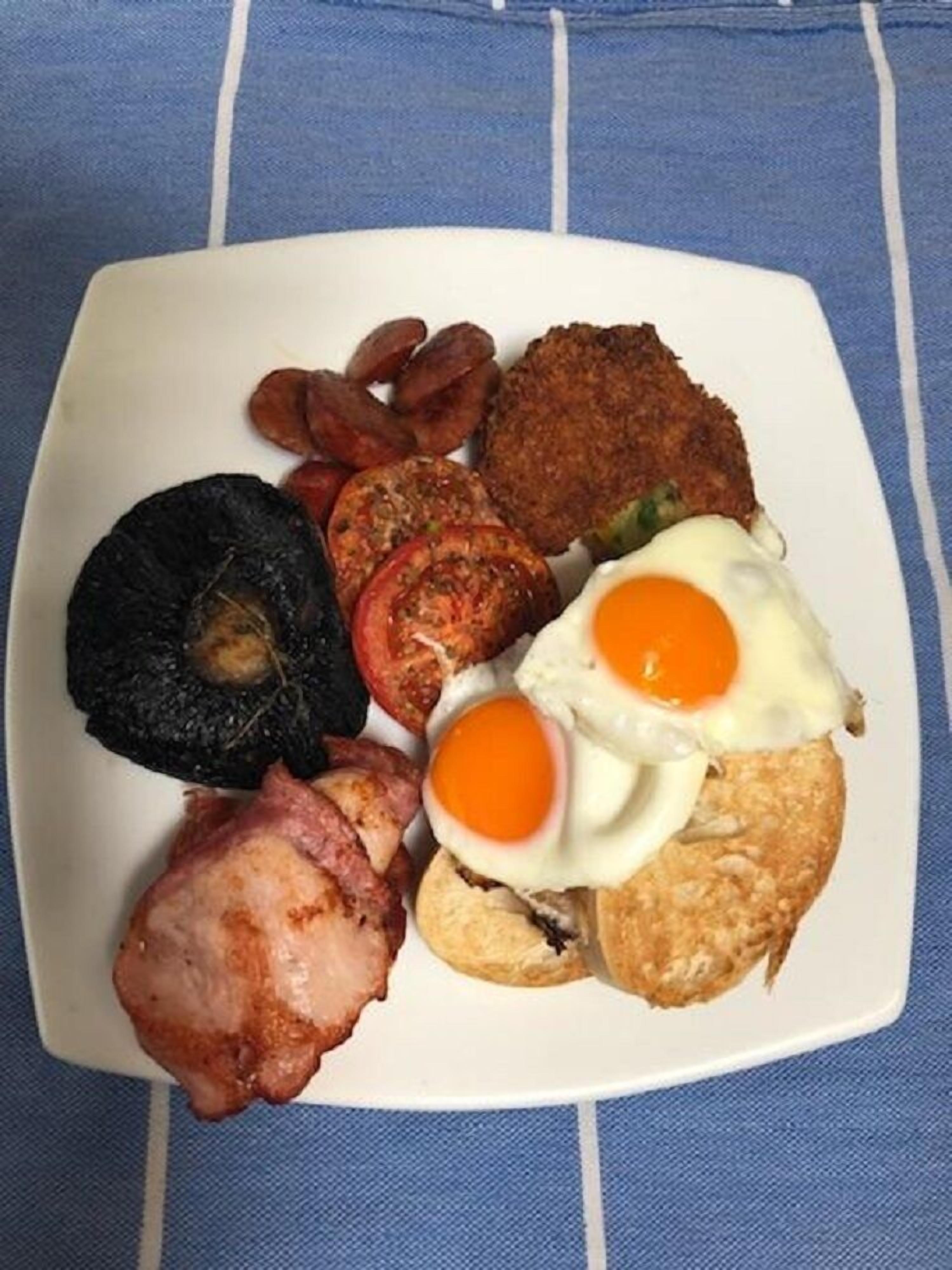 Un plato de comida para el desayuno con huevos, salchicha, tocino y tostadas.
