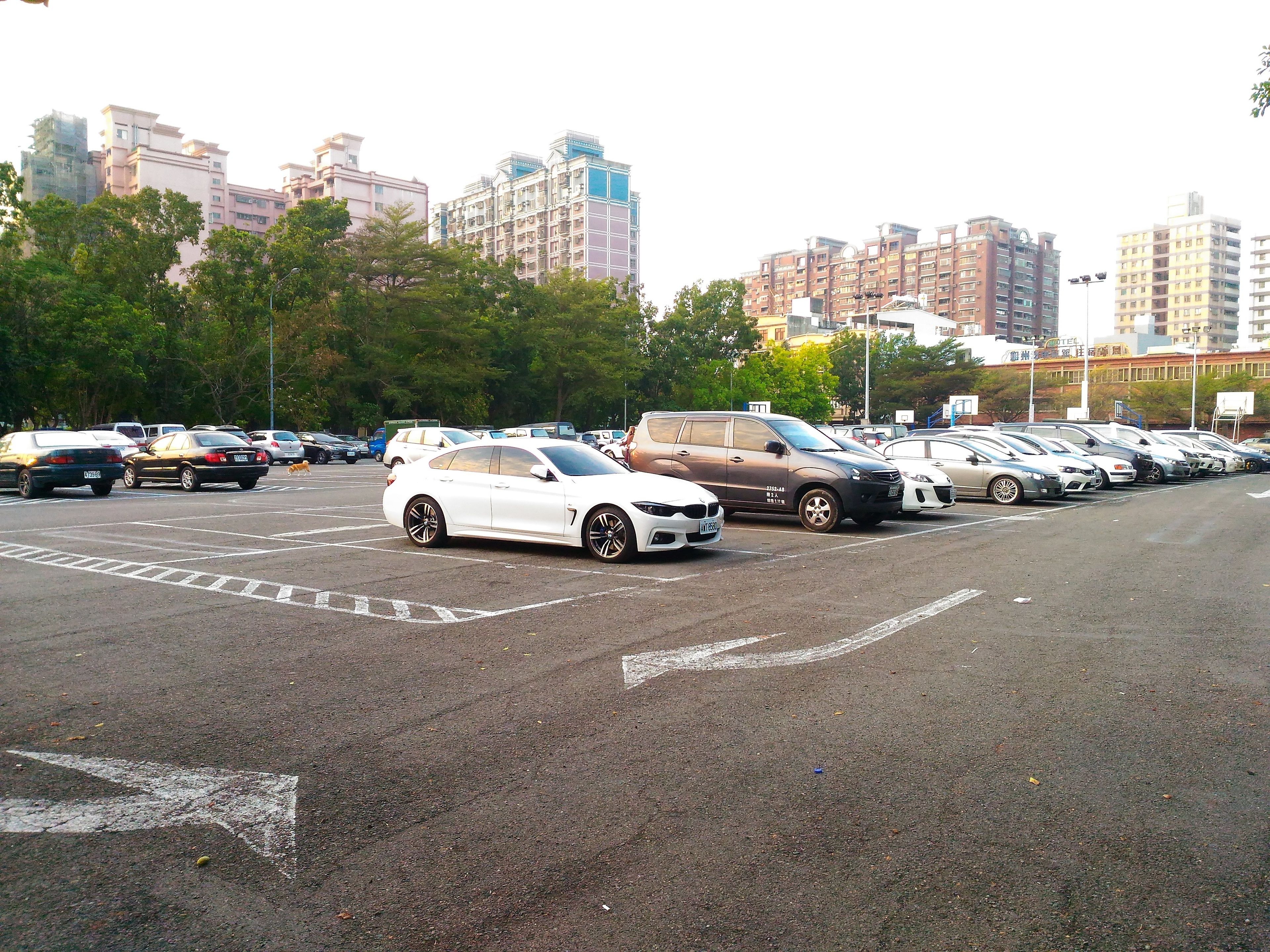A parking lot with multiple cars and buildings in the background.