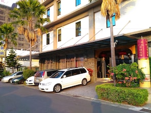 A modern hotel with a covered entrance, parked cars, and palm trees. - Wei Feng Exquisite Hotel Nanzi Branch (Kaohsiung)