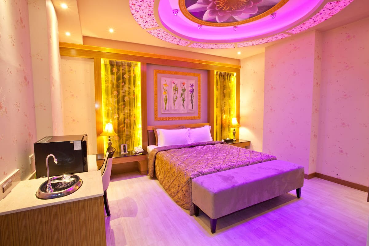 Une chambre d’hôtel comprenant un lit, des tables de chevet, un bureau avec un lavabo et un plafond décoratif.