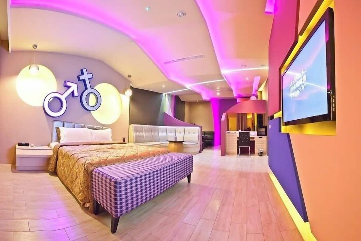 Une chambre d’hôtel moderne, dotée d’un grand lit, d’un bureau et d’une télévision.