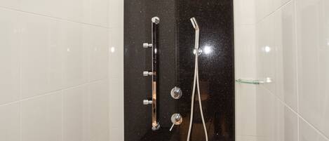 Un baño moderno con azulejos blancos, un box de ducha negro y una puerta de cristal.