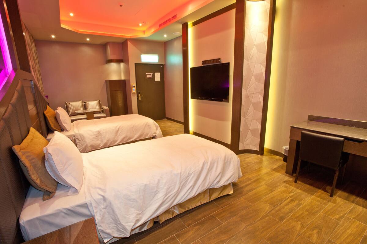 Une chambre d’hôtel avec deux lits, un bureau, une télévision et une porte avec une pancarte.