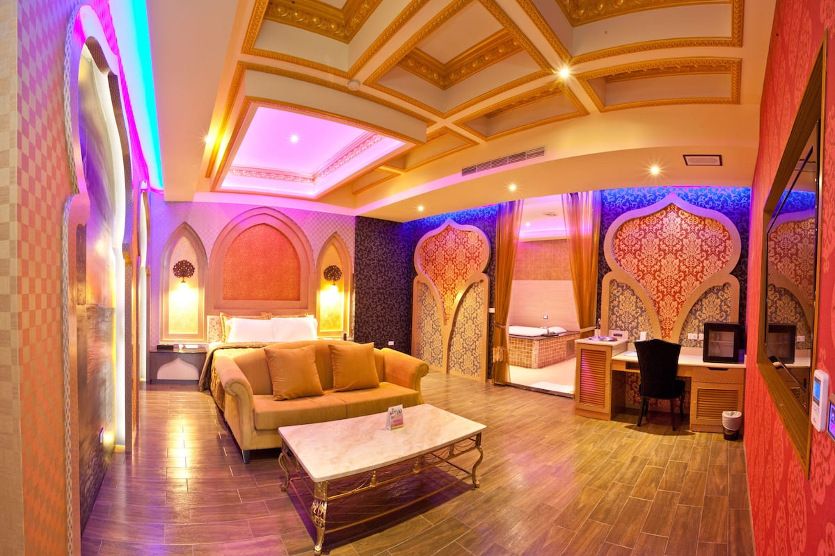 Une chambre d’hôtel luxueuse, dotée d’un canapé moelleux, d’une table basse en marbre et d’un bureau avec un ordinateur.