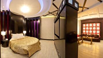 A modern hotel room with a large bed, a sitting area with a sofa and a coffee table, and a decorative wall with circular patterns.