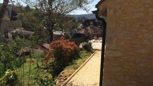 A stone building with a sloped roof, surrounded by a garden with various plants and a pathway. - House in the heart of the medieval city, ideal location and dream land (SARLAT)
