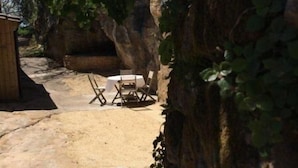 An outdoor patio area with stone flooring, two white chairs, and a wooden table. - House in the heart of the medieval city, ideal location and dream land (SARLAT)