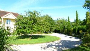 Zona residencial amb una avinguda corbada, una casa amb teulada vermella i diverses plantes.