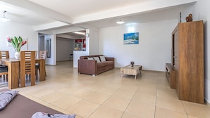 A spacious living area with a brown sofa, wooden coffee table, and a dining table with chairs. - Bottom of villa with pool (le Moule)