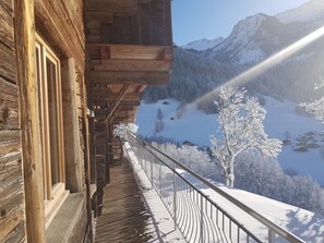 Ein Holzbalkon mit Blick auf eine verschneite Berglandschaft.