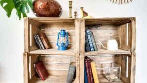 A wooden shelf with books, a lantern, a kettle, and decorative items. - Votre Escale - Le Petit Montmartre (Niort)