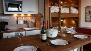 Une cuisine équipée d’un four à micro-ondes, d’un évier et d’un plan de travail en bois. On y trouve des bouteilles de vin, des verres et des assiettes sur le plan de travail.