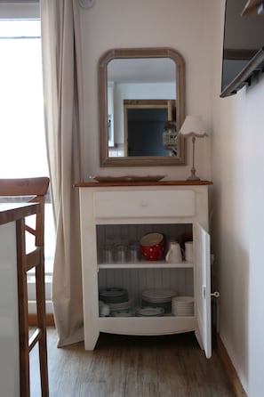 Une petite cuisine avec un meuble blanc, un miroir et une lampe.