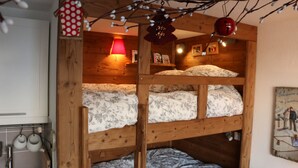 Une chambre avec des lits superposés, des murs en bois, une lampe rouge et un tableau encadré accroché au mur.