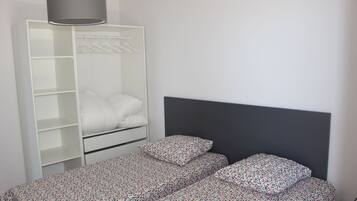 A bedroom with a bed, a wardrobe, and a hanging rack.
