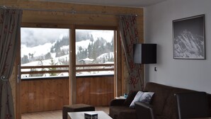 Ein gemütliches Zimmer mit Holzbalkon, einer Couch, einem Flachbildfernseher und einem gerahmten Bild an der Wand.