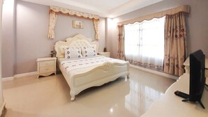 A bedroom with a large bed, a nightstand, a TV, and a window with curtains. - Baan Bua Sawhan Pool Villa Hua Hin (Hua Hin)