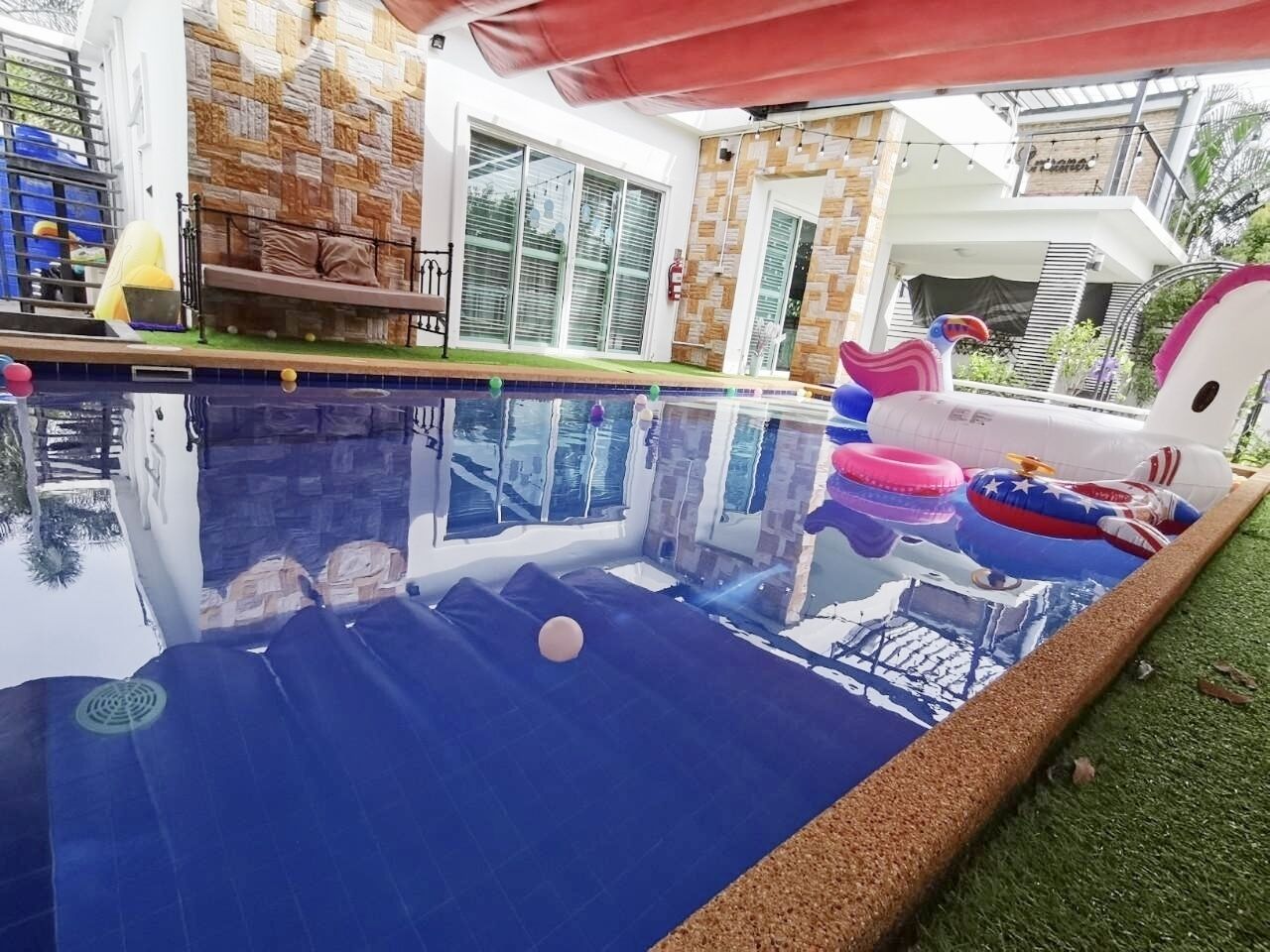 Una piscina all'aperto con giochi gonfiabili e uno sfondo a muro in pietra.