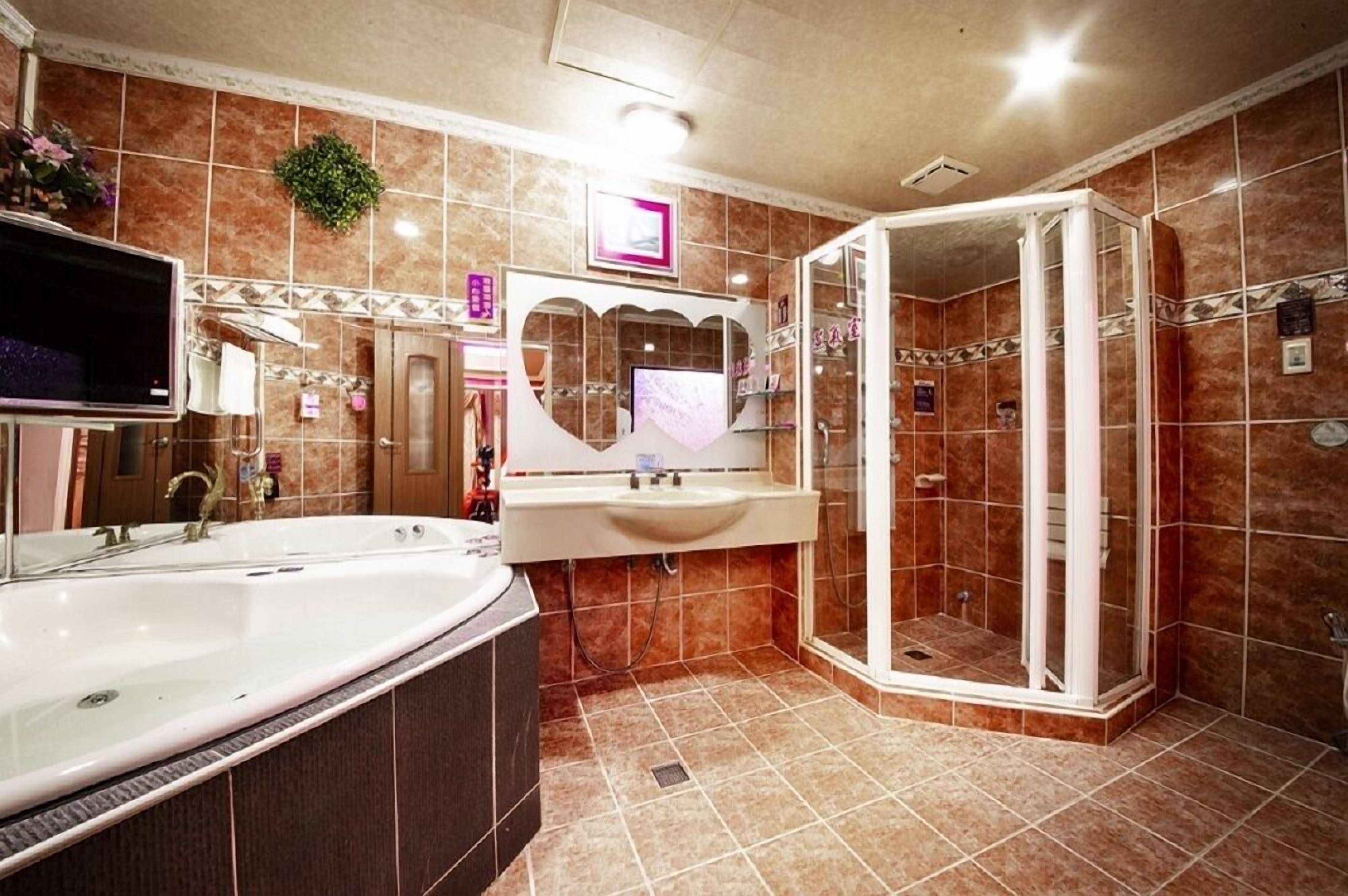 A bathroom with a large bathtub, a sink, and a glass-enclosed shower.