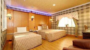 Habitación de hotel con dos camas, paneles de madera, pared a cuadros y una ventana con cortinas.