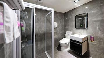 A modern bathroom with a glass shower enclosure, a toilet, and a sink with a mirror above it.