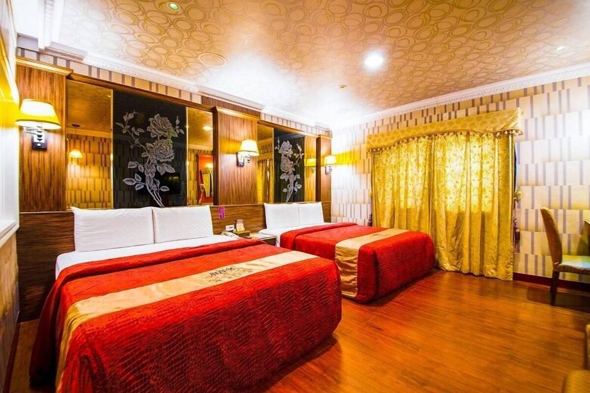 Ett hotellrum med två sängar, träpanel på väggarna, blommotiv på väggdekorationerna och en kristallkrona.
