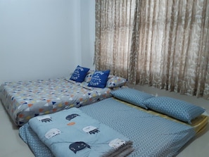 A room with two beds, each with patterned bedding and pillows, and a curtain in the background. - Baan Khunnatham Pool Villa Hua Hin (Hua Hin)