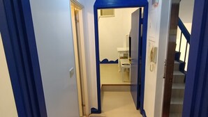 A hallway with blue walls and a white door at the end. - Shuili Heti (Shuili)