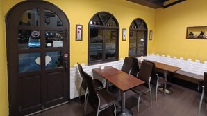 A restaurant with yellow walls, wooden tables, and arched windows. - Shuili Heti (Shuili)