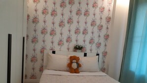 A bedroom with floral wallpaper, a bed with a floral bedspread, and a teddy bear on the pillows. - Baan Pimsamai Pool Villa Hua Hin (Hua Hin)