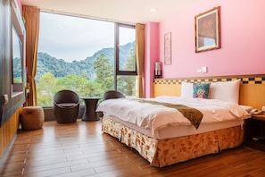 Un dormitorio con un ventanal grande, una cama, una silla y una pequeña mesa.