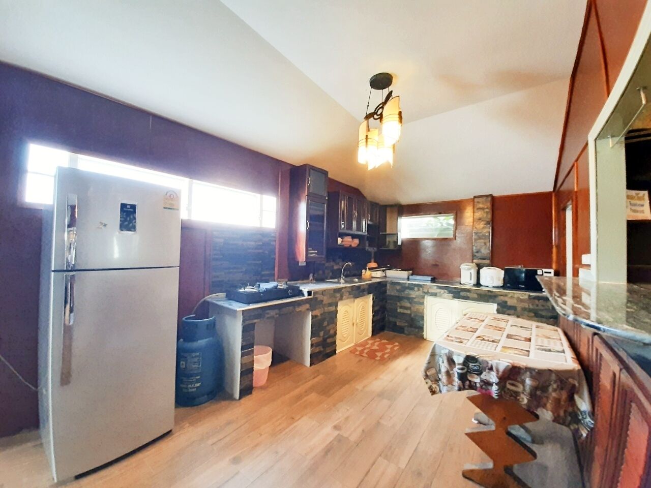Eine Küche mit Kühlschrank, Holzschränken, Spüle und Arbeitsplatte.