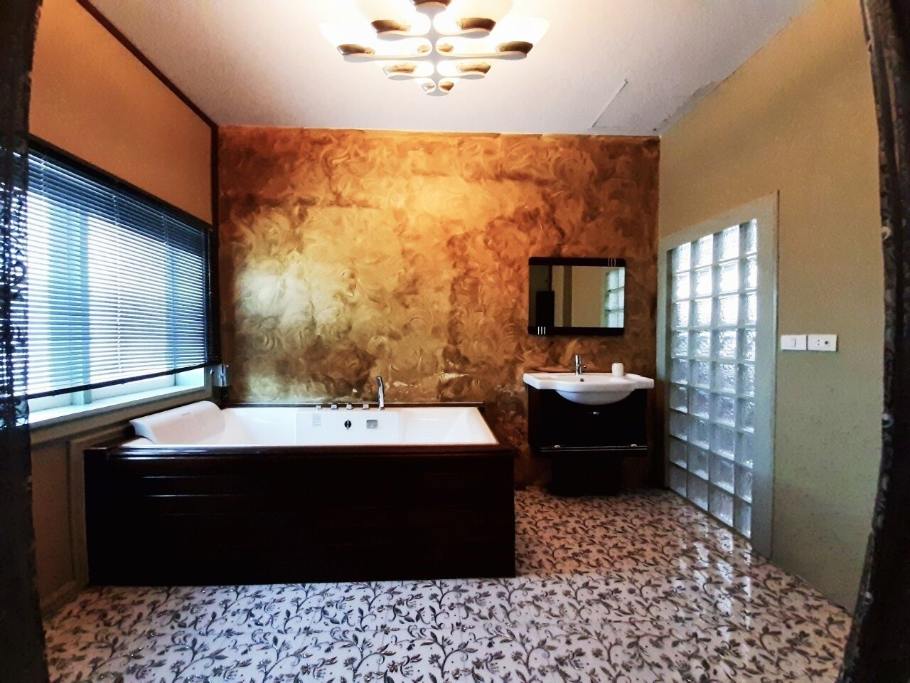 A bathroom with a large bathtub, two sinks, a mirror, and patterned flooring.