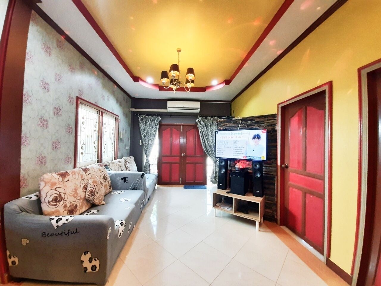 A living room with a sofa, a television, and a speaker system.