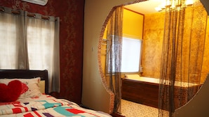 A bedroom with a bed, a window with curtains, and a bathroom visible through a semi-transparent partition. - Baan Rainy Pool Villa Hua Hin (Hua Hin)