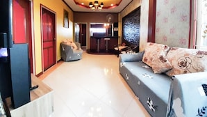 A spacious living area with a sofa set, a television, and a kitchen area in the background. - Baan Rainy Pool Villa Hua Hin (Hua Hin)