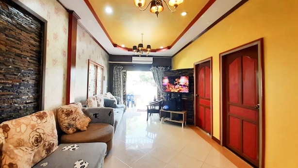 A living room with a sofa, TV, and a red door. - Baan Rainy Pool Villa Hua Hin (Hua Hin)