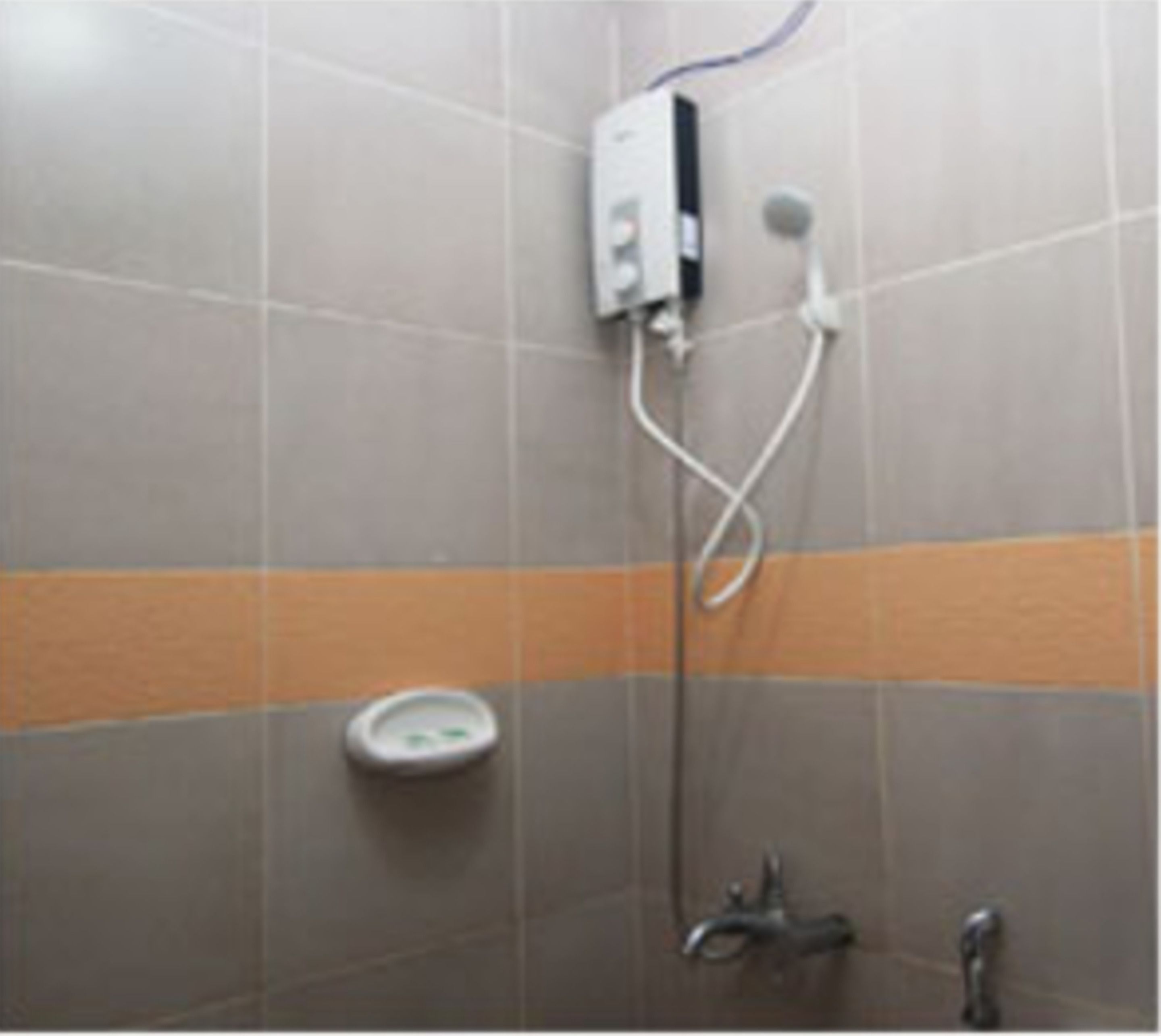 Et bruseområde med brusehoved, kontrolpanel på væggen og et toilet.
