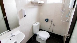 A small bathroom with a white sink, toilet, and shower. There is a towel rack above the toilet and a soap dispenser on the wall. - Sg Pelek Hotel (Sungai Pelek)