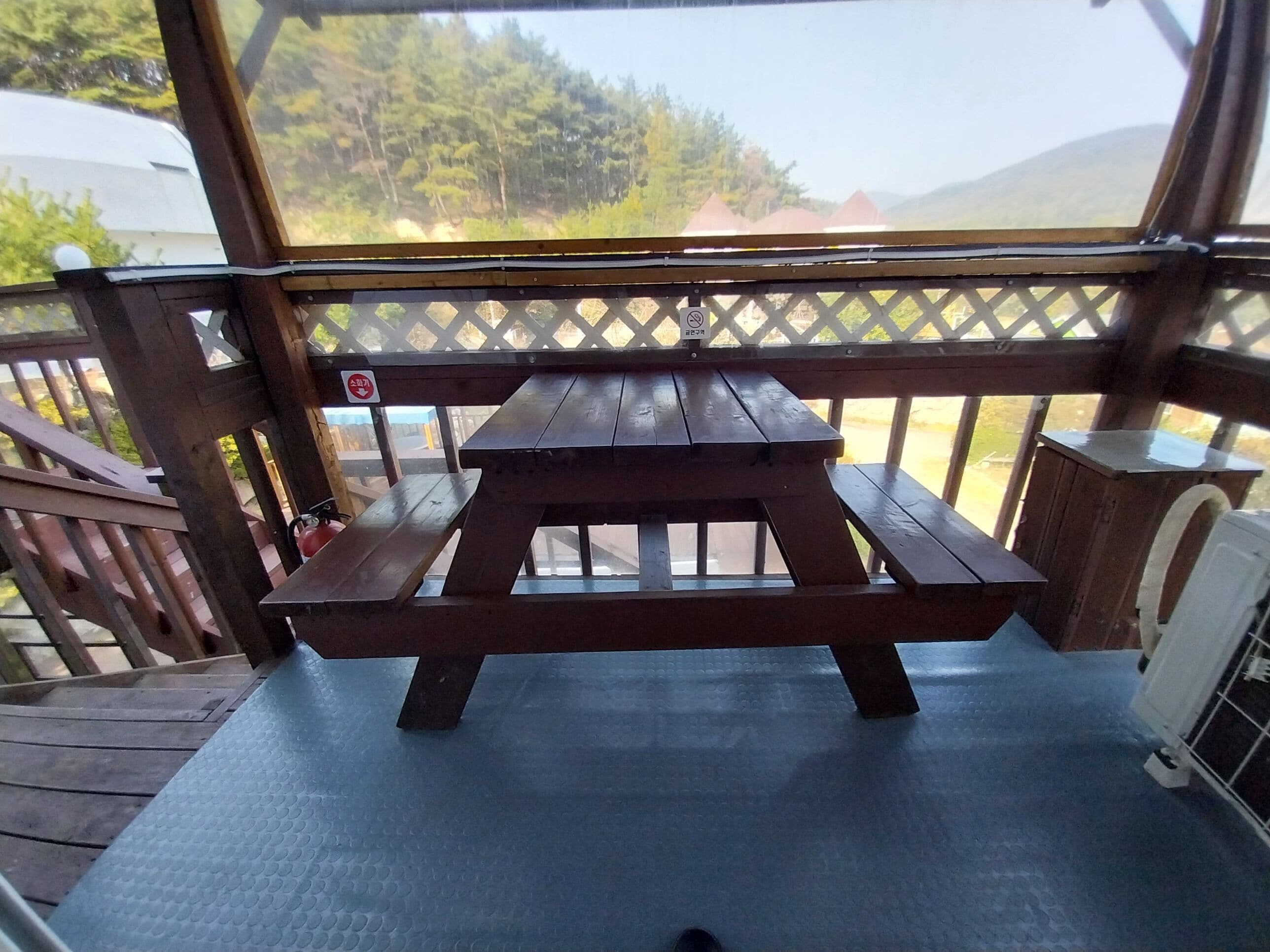 A wooden picnic table with benches on a deck with a lattice railing.