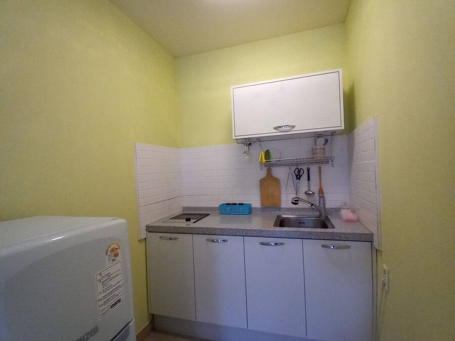 Una cocina compacta con armarios blancos, un lavamanos y una pequeña encimera.